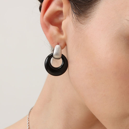 A detailed close-up shot of a model wearing a TIKOO black onyx earring, highlighting the platinum plating and gemstone texture.