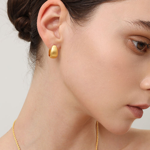 Detailed view of the chatoyant brown tiger eye texture and 18k gold plated finish on TIKOO designer earrings.