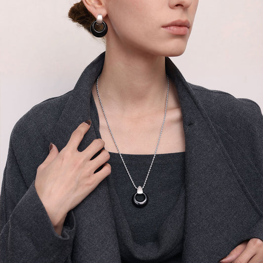 Model wearing TIKOO black onyx pendant necklace with a charcoal grey coat, showcasing a professional and minimalist jewelry style.