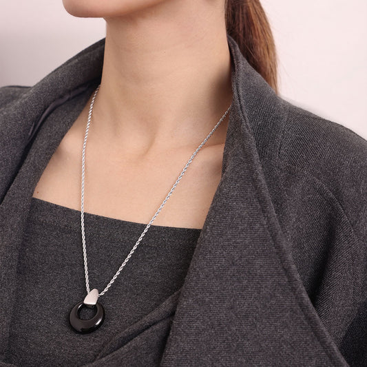 Close-up view of the natural black onyx halo pendant and platinum plated rope chain on a model.