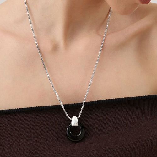 Model wearing TIKOO black onyx pendant necklace with a charcoal grey coat, showcasing a professional and minimalist jewelry style.