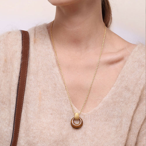 Close-up of a model wearing TIKOO tiger eye necklace, styled with a beige knit sweater for an old money aesthetic.