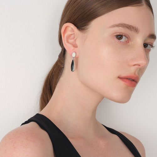 Side view of a model wearing TIKOO black onyx and white leather sculptural dangles with a black top.