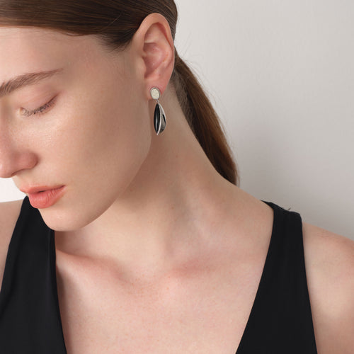 Close-up portrait showcasing the fluid design and platinum-plated finish of TIKOO leather and stone earrings.