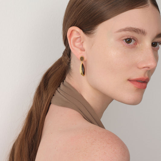 Side profile of a model wearing TIKOO tiger's eye and leather sculptural dangles, highlighting the rich brown tones.