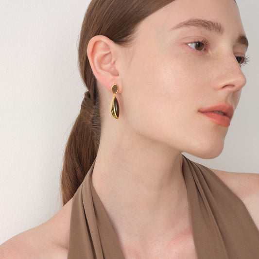 Close-up portrait of TIKOO thick 18K gold plated earrings on a model, showcasing the unique leather and stone texture.