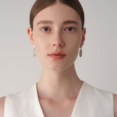 Front view of a model wearing TIKOO white stone and leather drop earrings, showcasing the elegant and clean minimalist look.