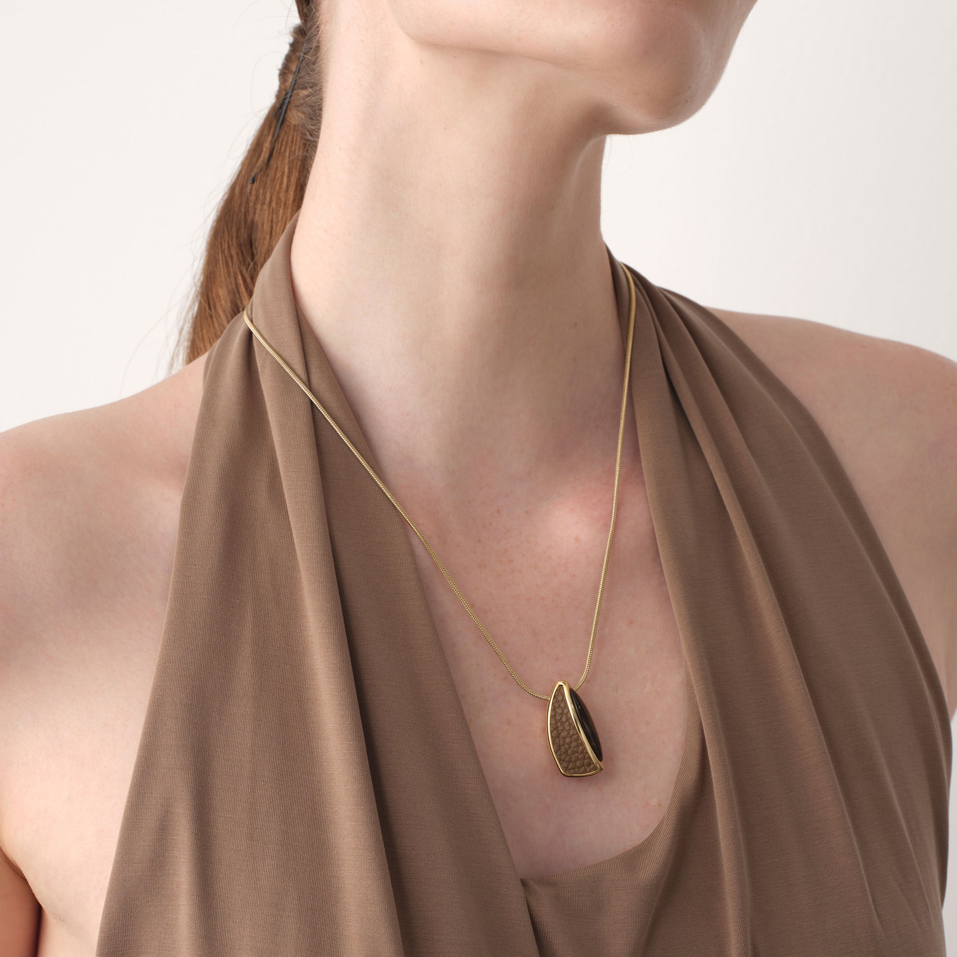 Close-up of TIKOO thick 18K gold plated pendant on a model, highlighting the unique leather texture and natural stone.