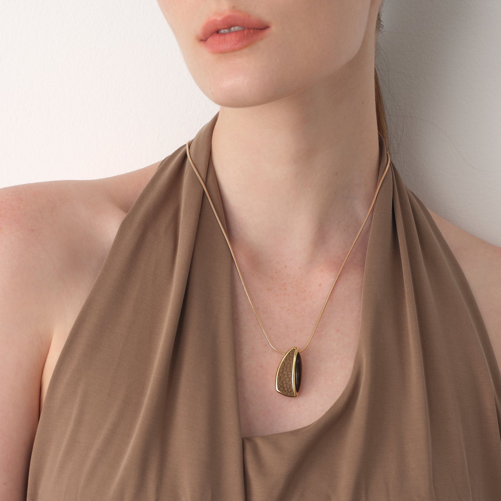 Close-up of TIKOO thick 18K gold plated pendant on a model, highlighting the unique leather texture and natural stone.