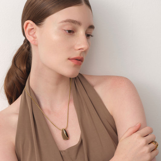 Model wearing TIKOO tiger's eye and leather necklace, showcasing the earthy brown tones and fluid sculptural design.