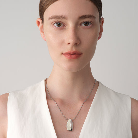 A model wearing the TIKOO white stone and leather necklace with a white vest, showcasing a modern, clean fashion aesthetic.