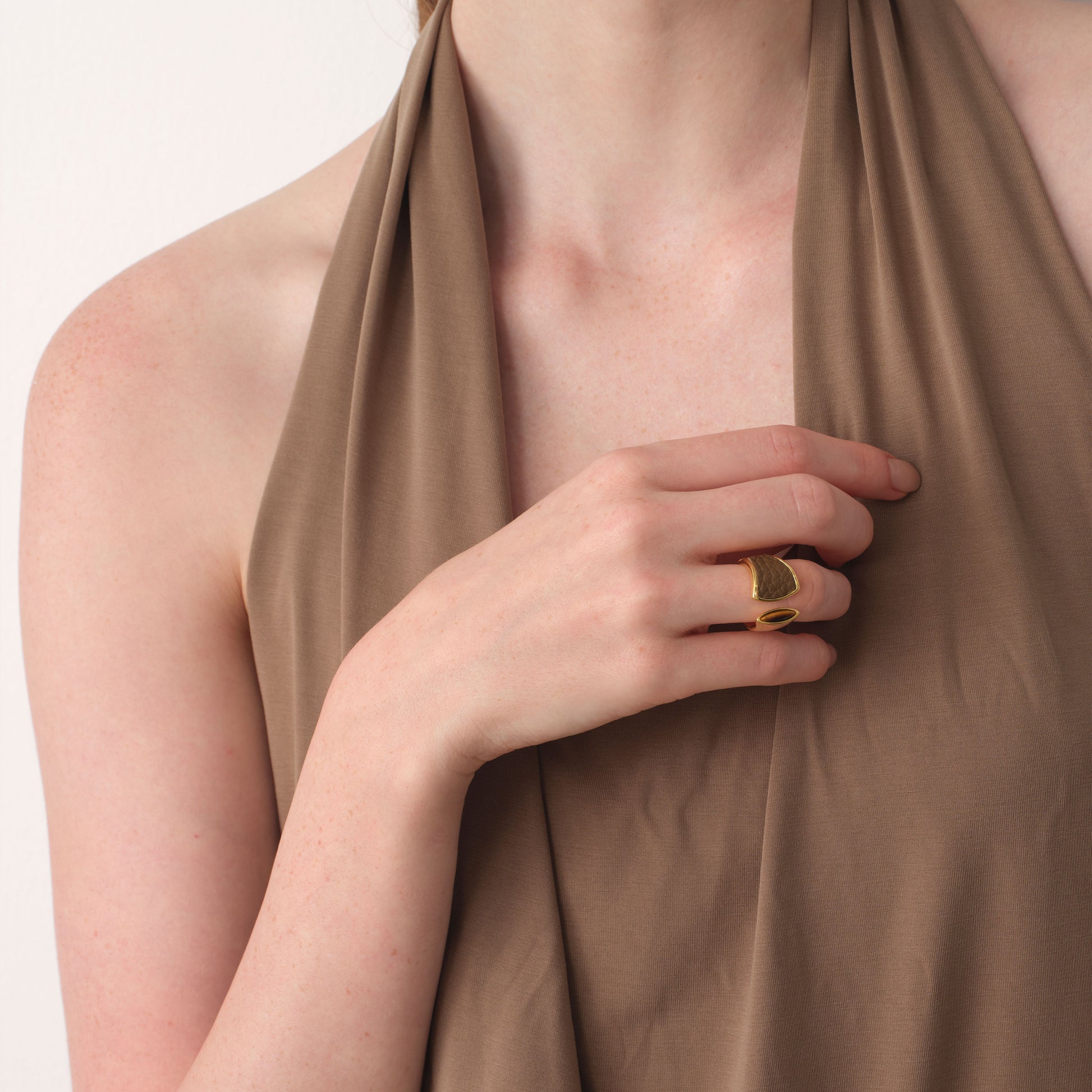 Lifestyle shot of a model styling the TIKOO thick 18K gold plated ring with a brown earthy-tone outfit.