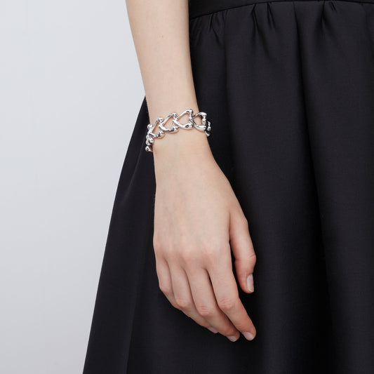 Fashion model styling the TIKOO chunky silver-tone heart bracelet with a black dress for a minimalist look.