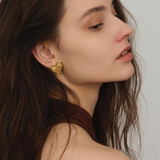 Close-up of TIKOO heavy 18K gold plated heart earrings on a model, highlighting the fluid metal texture.