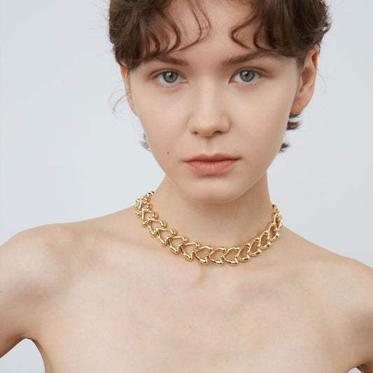 A model wearing the TIKOO gold heart statement choker, showcasing its elegant fit and high-shine finish.