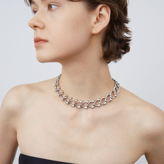 A model wearing the TIKOO silver-tone heart statement necklace, showcasing its modern choker fit.