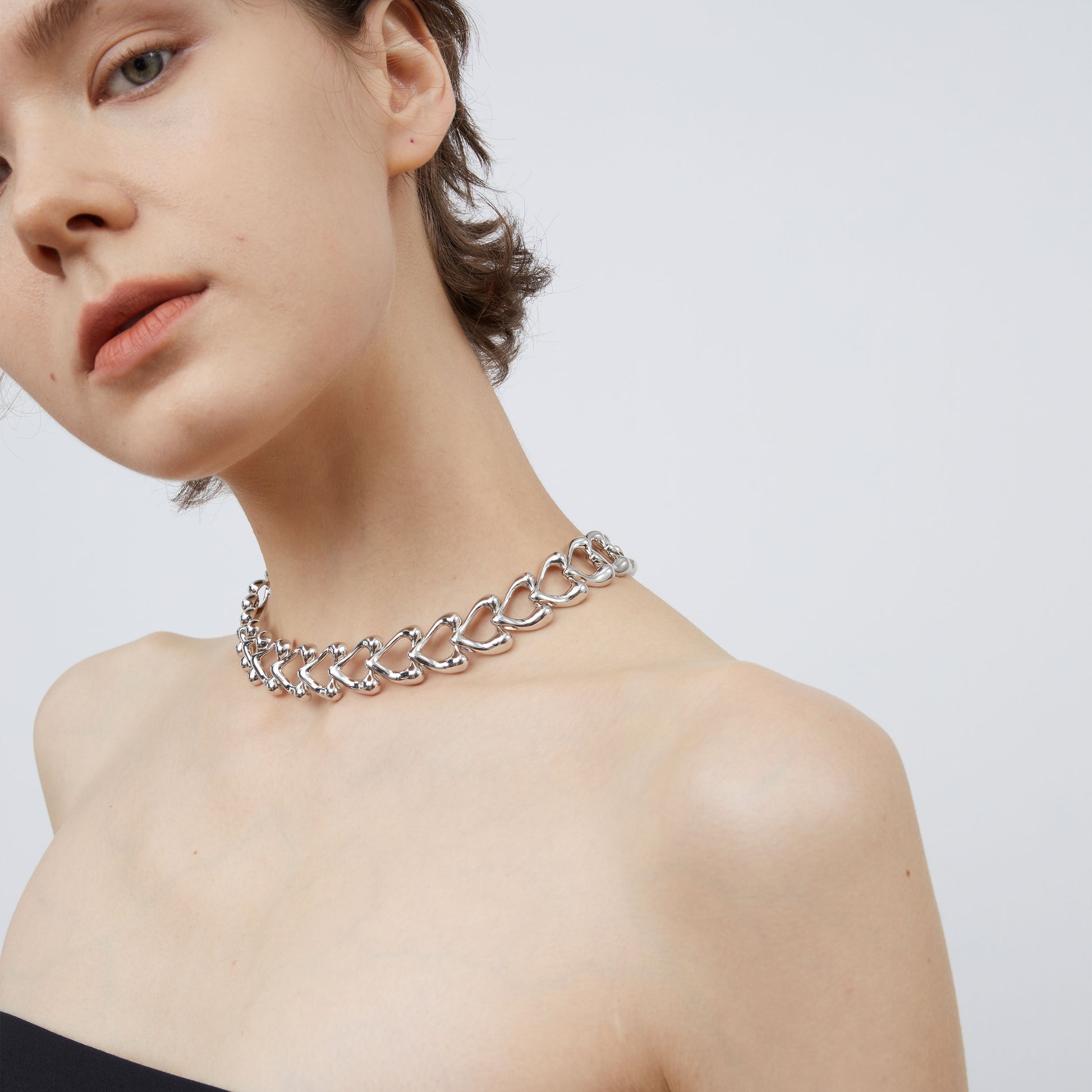 Detailed side view of the TIKOO thick rhodium-plated heart chain necklace, highlighting its lustrous metallic finish.