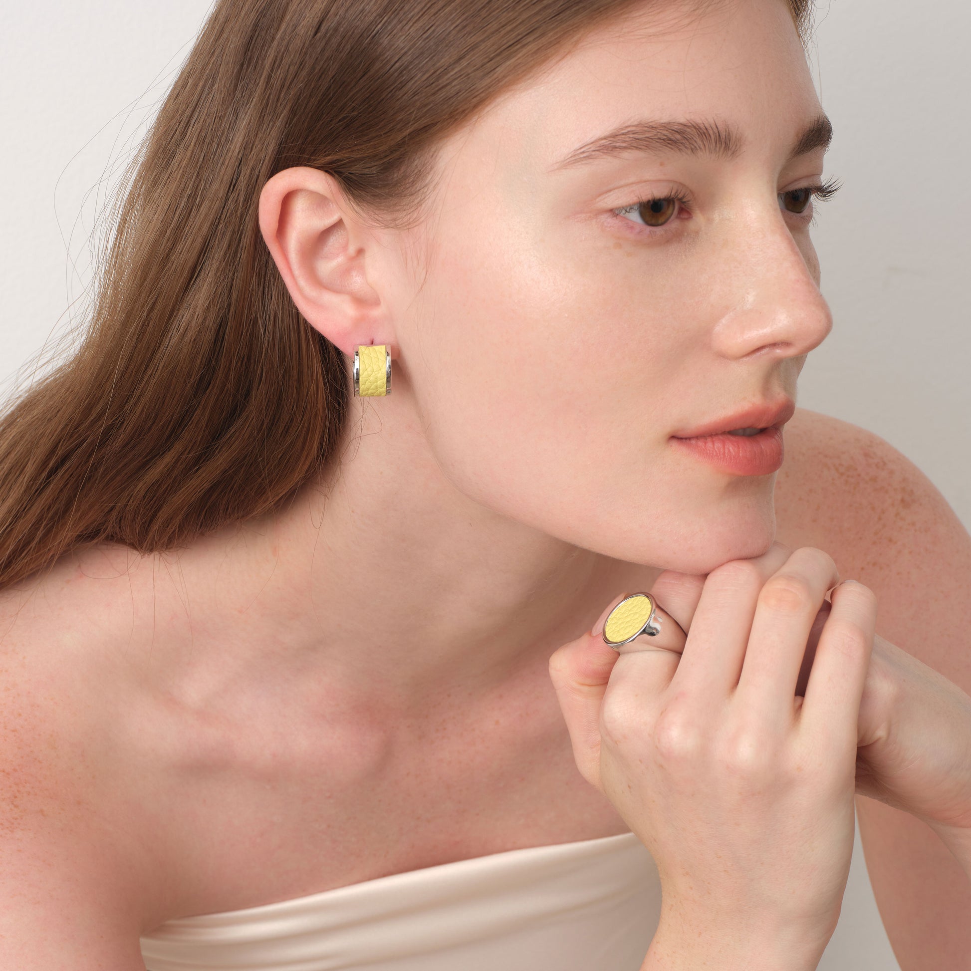 Model showcasing a matching TIKOO jewelry set featuring yellow leather earrings and a signet ring for a vibrant, coordinated look.
