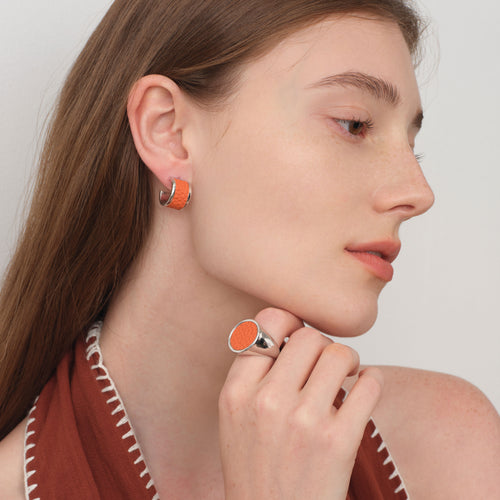 Model wearing the TIKOO orange leather signet ring and matching leather hoop earrings for a coordinated luxury look.