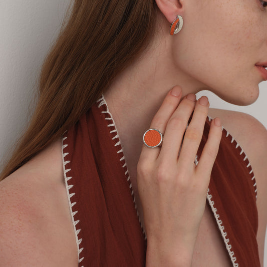 Close-up of model wearing the TIKOO orange leather statement ring, highlighting the textured leather grain and thick metal band.