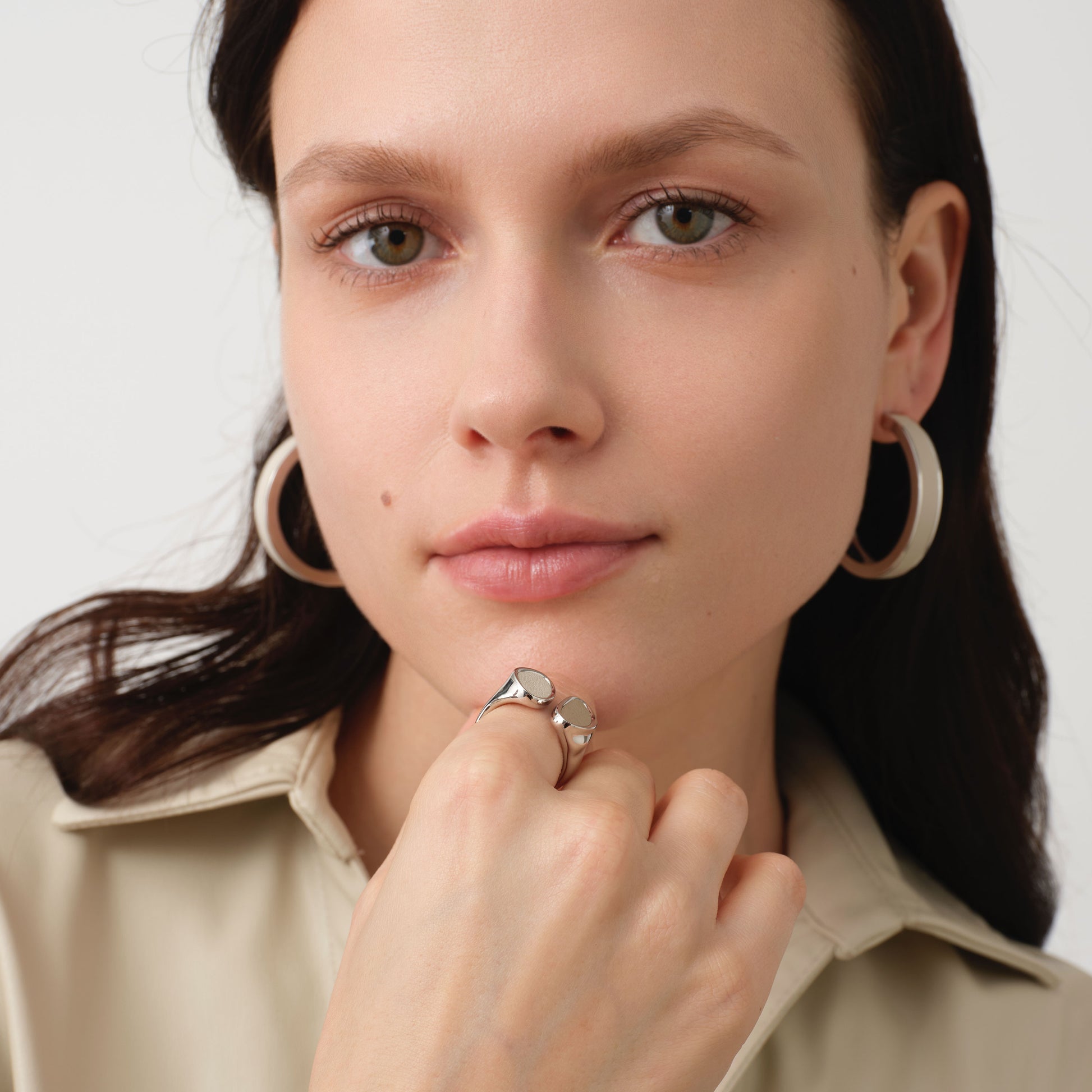 Front view of model wearing TIKOO beige leather hoops and matching ring, highlighting the textured leather and brilliant silver shine.