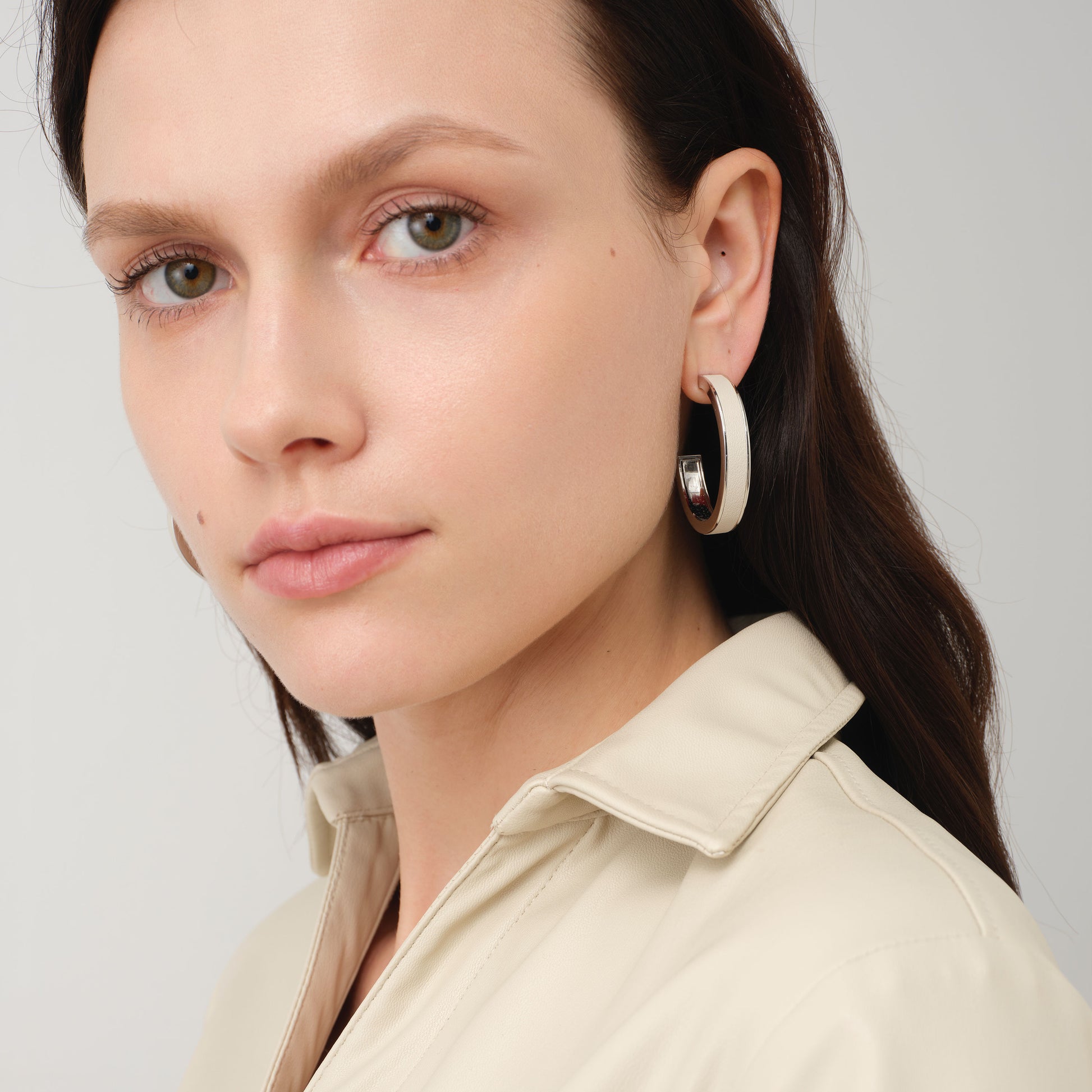 Fashion model wearing TIKOO large white leather hoop earrings, showcasing the clean girl aesthetic and minimalist jewelry trend.