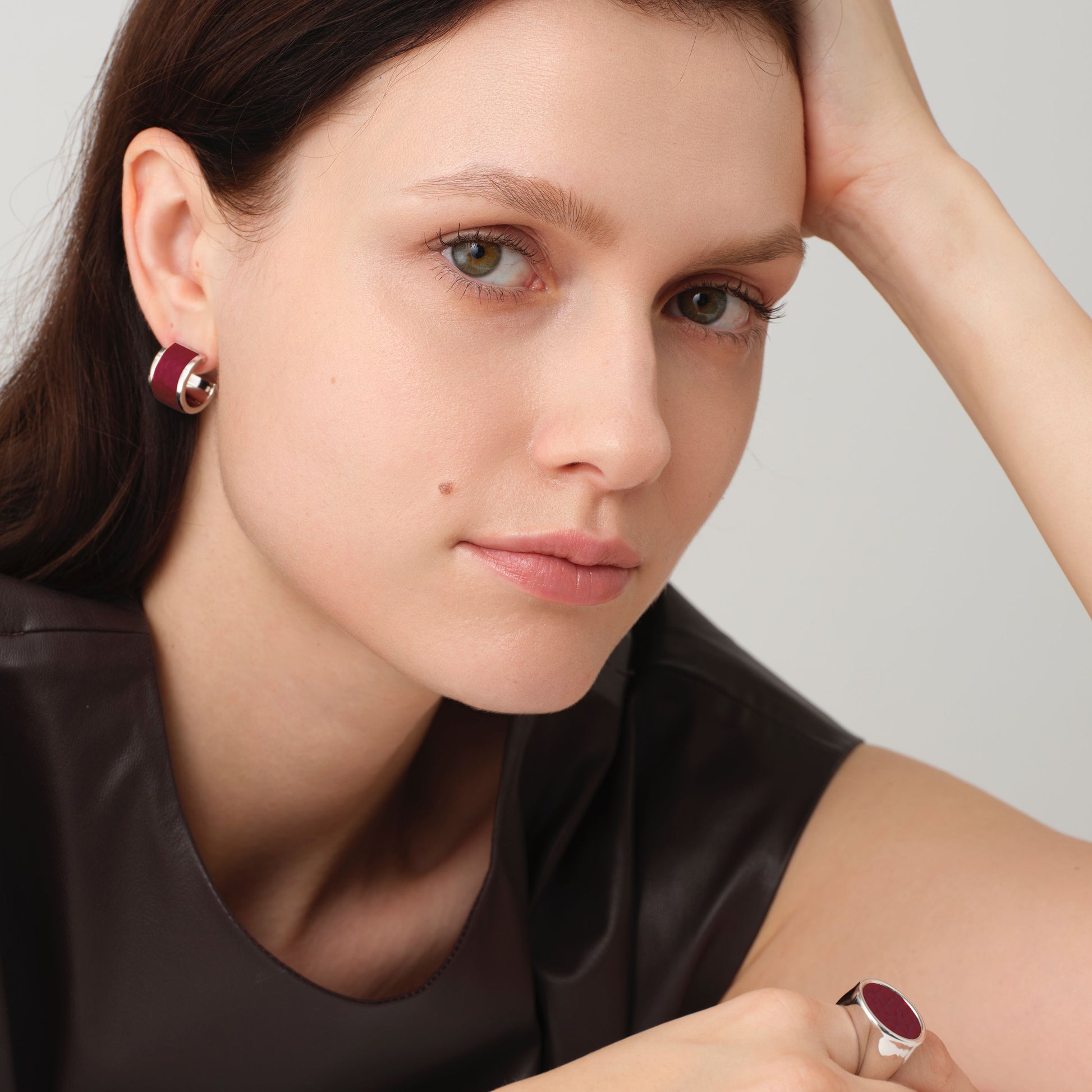 Model showcasing the TIKOO burgundy leather inlay earrings and matching ring, demonstrating the rich color contrast and modern fashion styling.