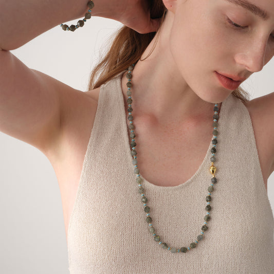 Close-up of a model wearing a long labradorite gemstone necklace by TIKOO, showcasing the elegant drape and high-quality gold accents.