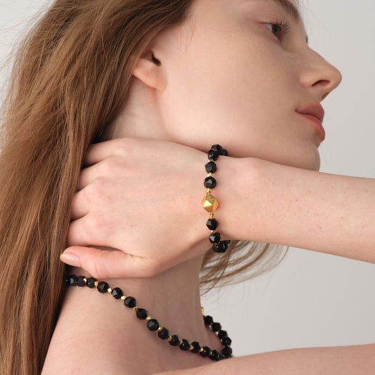 Close-up shot of a model wearing the TIKOO black onyx gemstone bracelet, highlighting the elegant fit and luxurious gold accents.