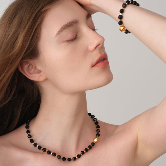 A model showcasing the TIKOO black onyx jewelry collection, including the beaded bracelet and matching necklace for a complete high-fashion look.