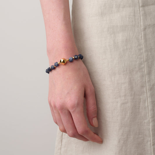 Close-up of model's wrist wearing TIKOO blue sodalite gemstone bracelet with a neutral linen dress.