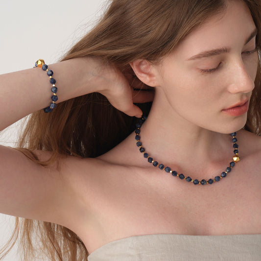 Model wearing TIKOO blue sodalite necklace and matching bracelet, highlighting the thick 18K gold plating and natural stone texture.