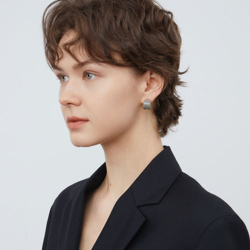 Side view of a model wearing TIKOO minimalist cool grey enamel hoop earrings.