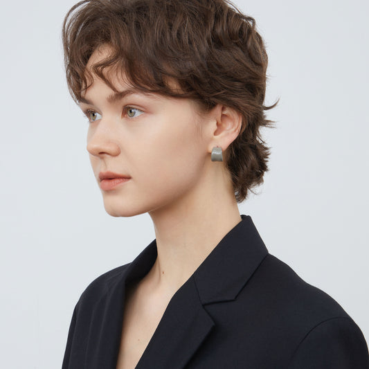 Side view of a model wearing TIKOO minimalist cool grey enamel hoop earrings.