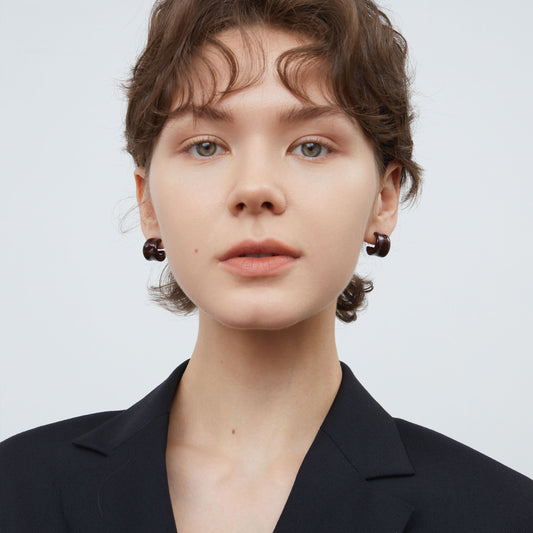 Front view of a model wearing TIKOO espresso brown enamel hoop earrings with a black blazer.