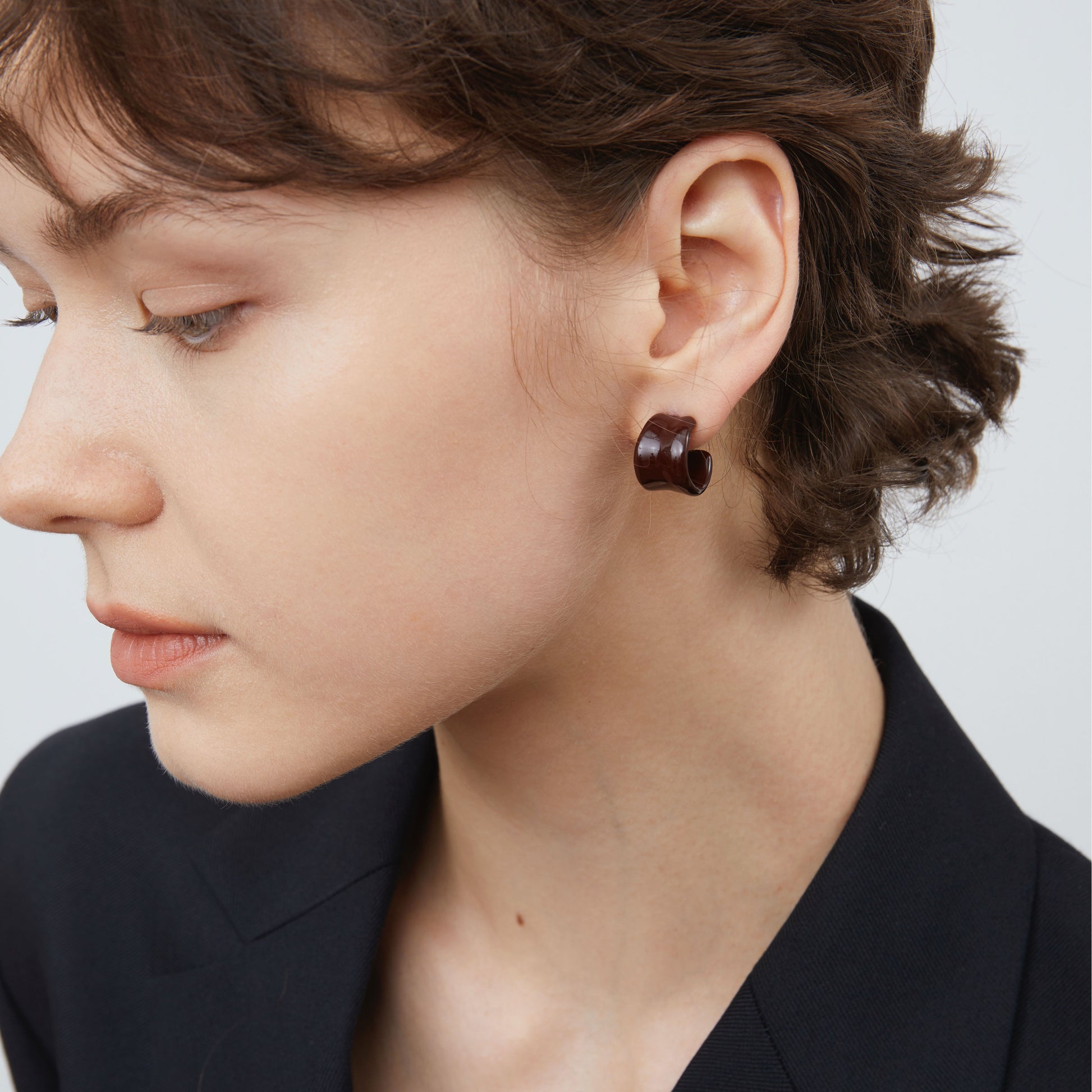 Side view of TIKOO dark brown enamel C-shape earrings highlighting the thick platinum plating.