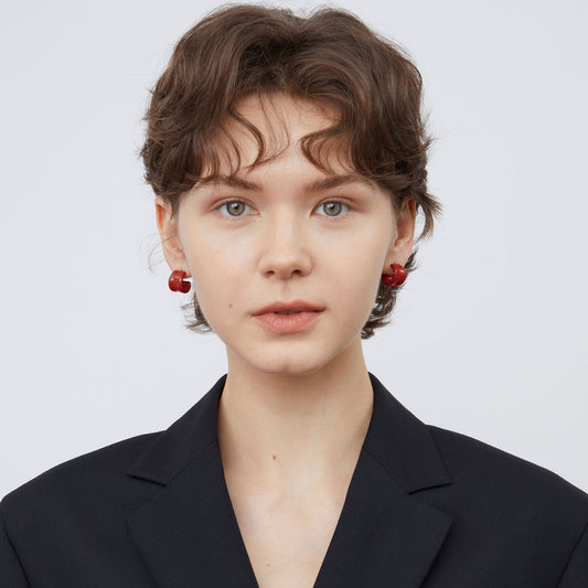 Front view of a model wearing TIKOO minimalist deep red enamel hoop earrings, showcasing the color and size.