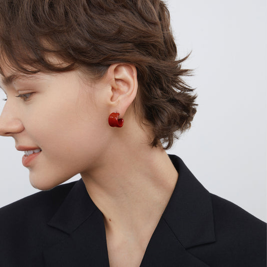 Side profile view of a model wearing TIKOO C-shaped dark red enamel earrings, highlighting the sculptural design.