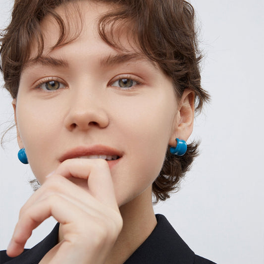 Close up of a woman wearing TIKOO azure blue enamel earrings.