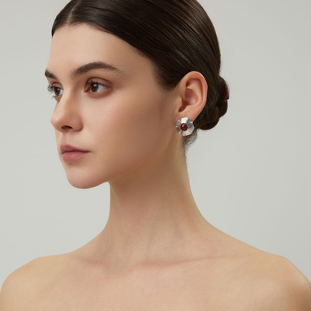 Close-up shot showing the intricate geometric ridges of the platinum-plated red jasper earrings.
