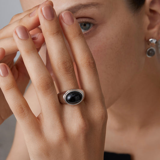 Close-up of the TIKOO black onyx signet ring on a model's hand, showcasing its sculptural chunky design.
