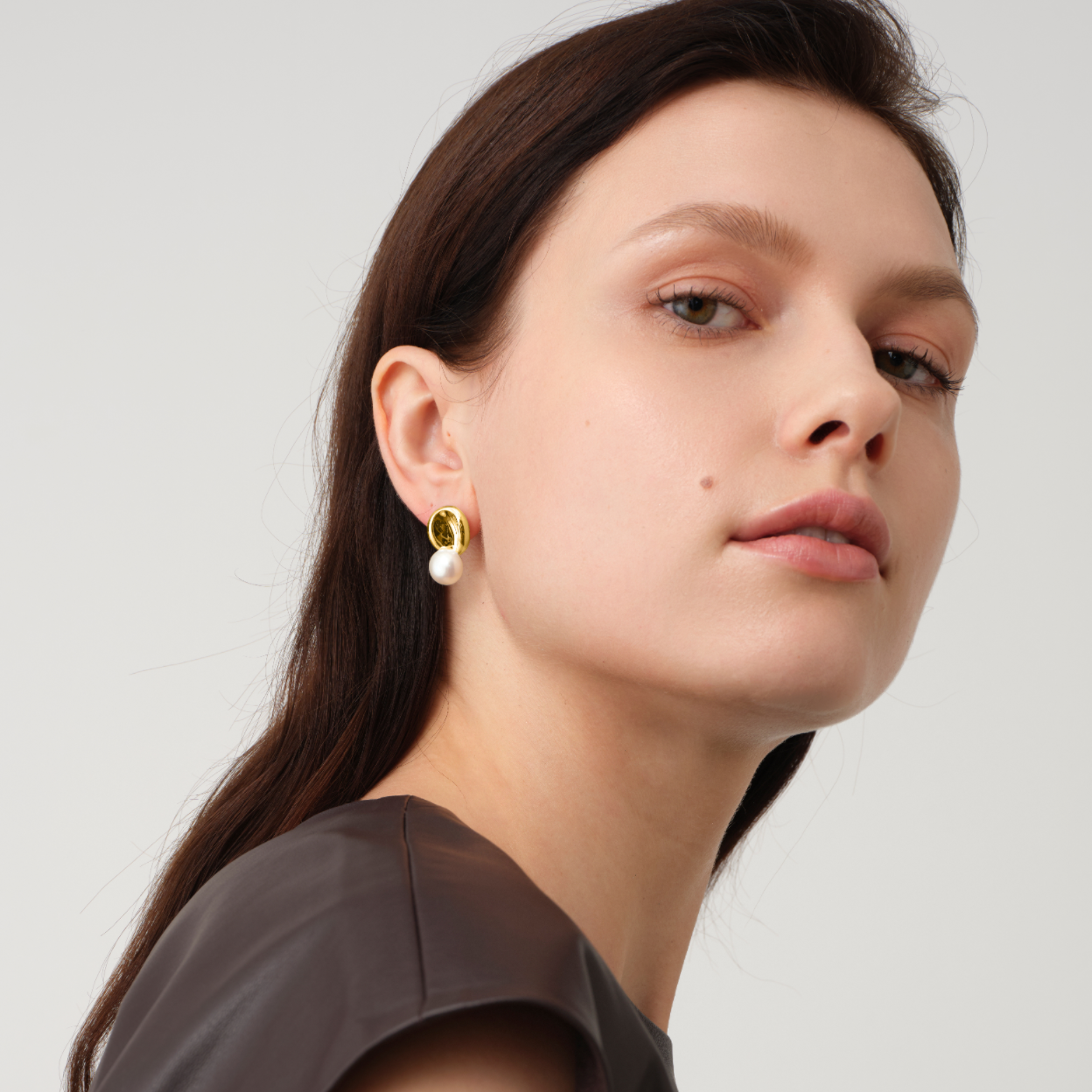 Close up of a model wearing TIKOO original designer pearl earrings with thick 18K gold plating.