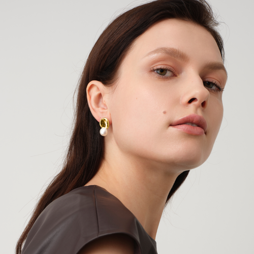 Close up of a model wearing TIKOO original designer pearl earrings with thick 18K gold plating.