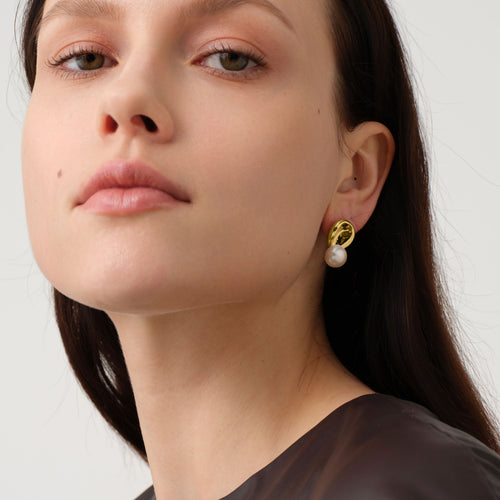 Close up of a model wearing TIKOO original designer pearl earrings with thick 18K gold plating.