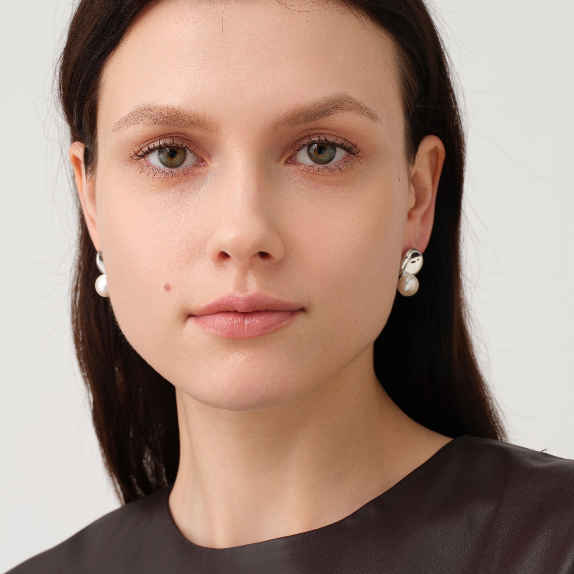 Front view of a model wearing TIKOO pearl earrings, showcasing the modern minimalist jewelry style.
