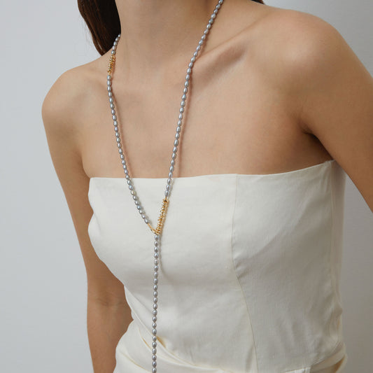 Close-up of model styling TIKOO grey Swarovski pearl necklace as a Y-shaped lariat with 18K gold toggle clasp visible.