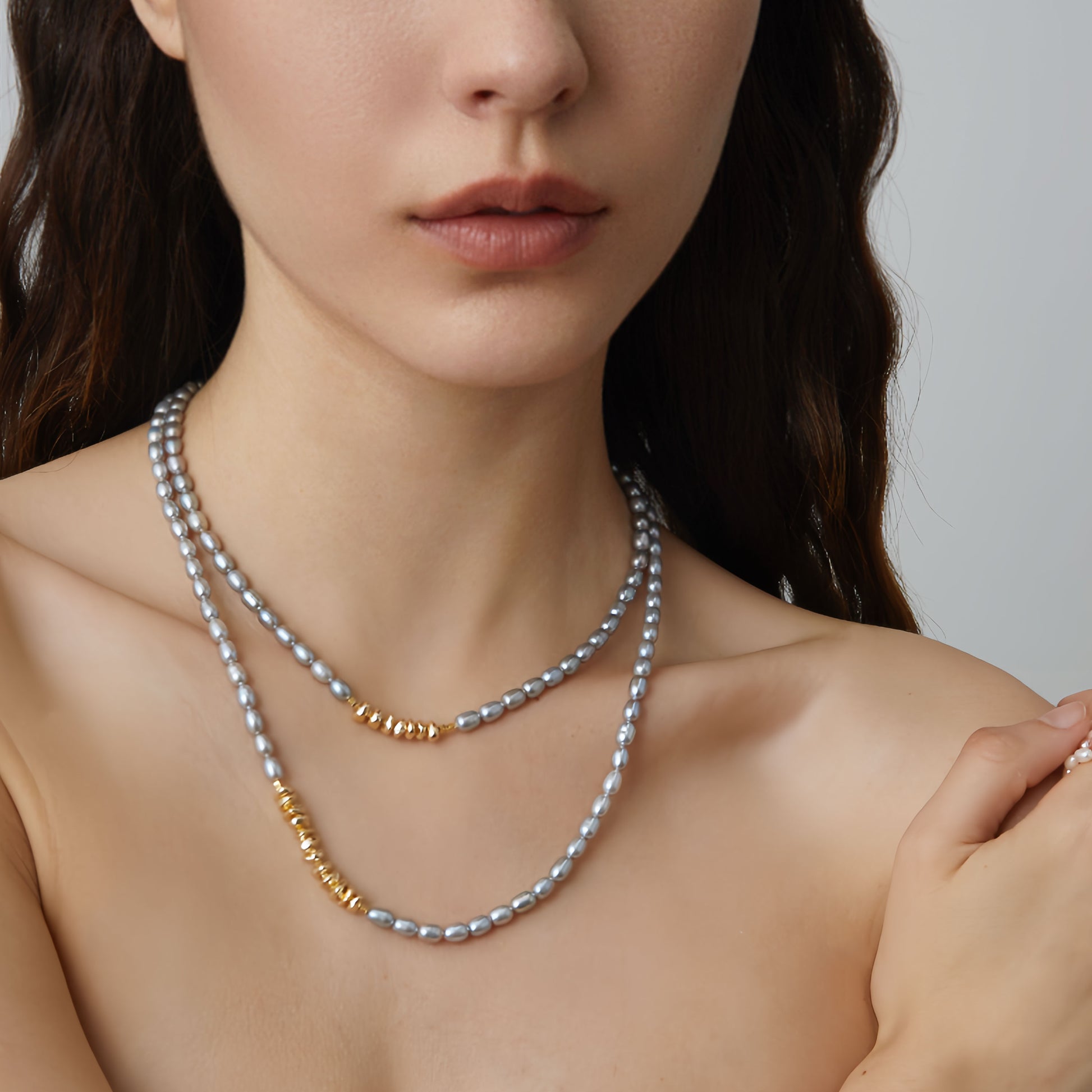 High-fashion close-up of model wearing TIKOO grey Swarovski pearl necklace as a double-strand choker, showing rich gold plating detail.