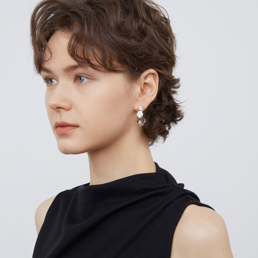 Model wearing TIKOO white shell wave earrings, showcasing the organic curved design and lustrous finish.