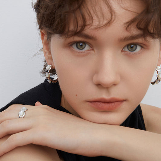 Front view of a model wearing TIKOO platinum plated mother of pearl hoops, highlighting the elegant iridescent glow.