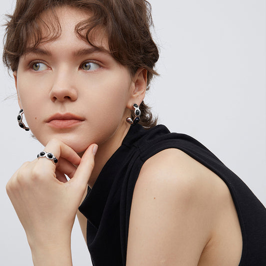Lifestyle shot of TIKOO liquid metal scalloped hoops with black onyx on a model.